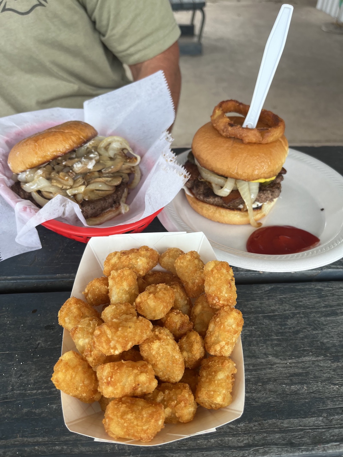 Grilled onion and mushroom burger next to a Double Ringer Burger and tots